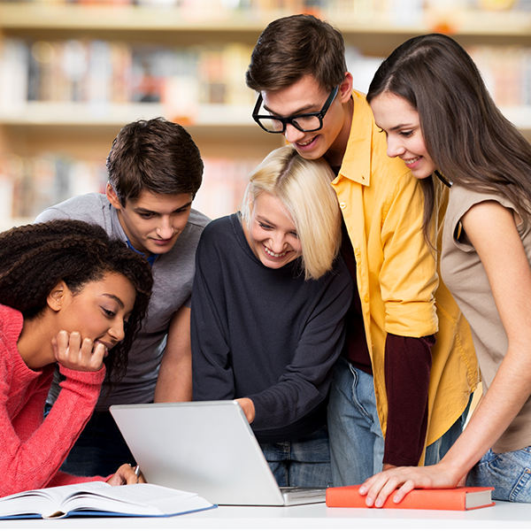 group of smiling boys an girls reading from a laptop